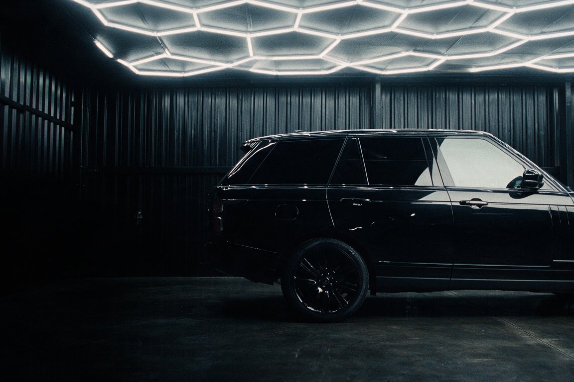 Side profile of a dark car showing tinted rear glass under studio lighting